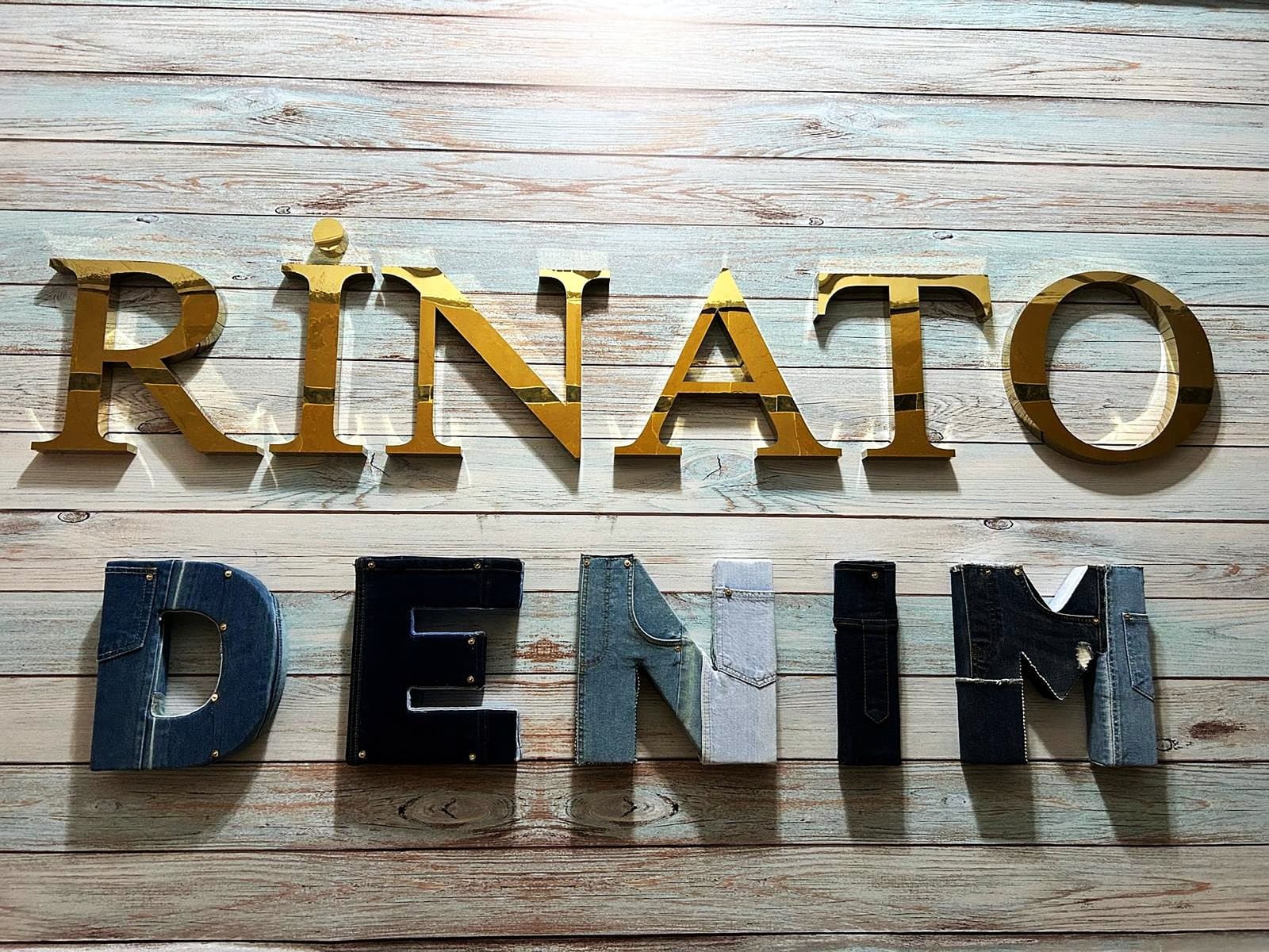 The Rinato Denim wall at Bağcılar — RINATO in gilded letters above DENIM cut from worn jeans