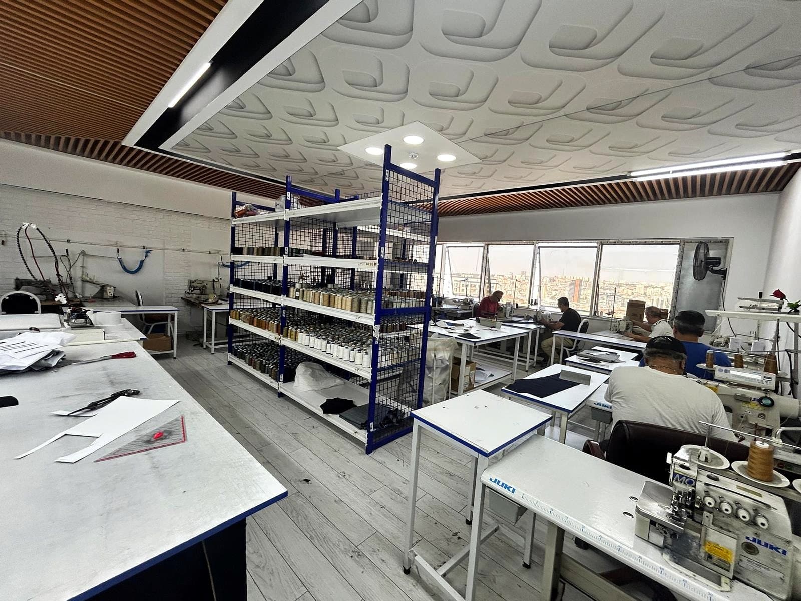 Rinato's sewing floor at Bağcılar — the cutting tables, the thread racks and the machine line